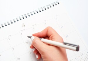 Female hands write in calendar on white background, concept of planning.